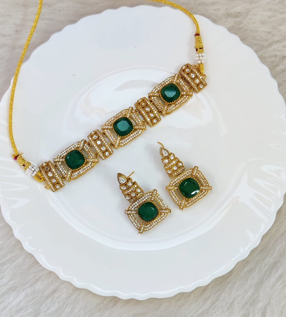 Model wearing a Forest Gem Choker with deep green crystals and gold-plated chain against a white neckline